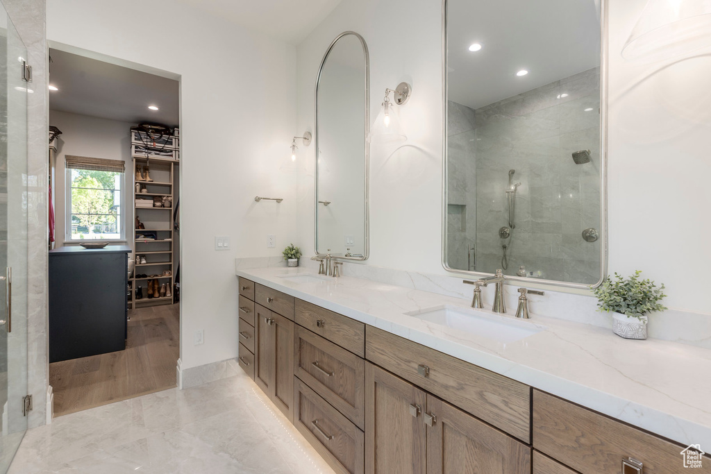 Bathroom featuring double vanity, a shower stall, recessed lighting, and a spacious closet