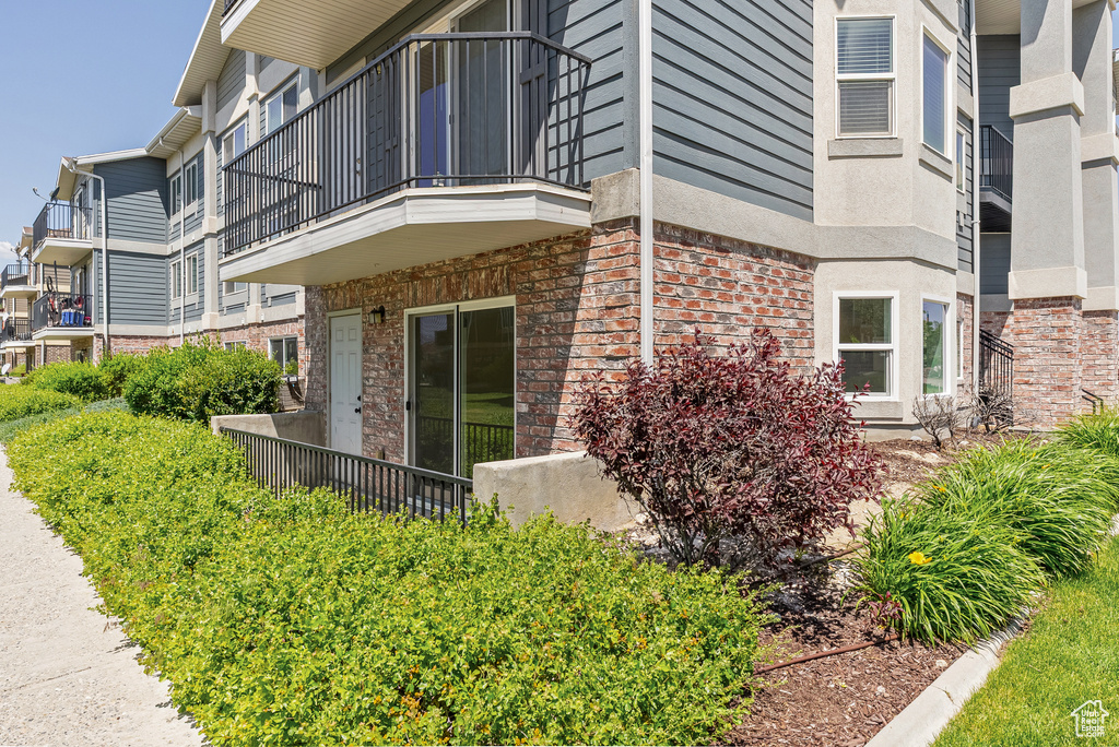 View of side of home with brick siding and a balcony