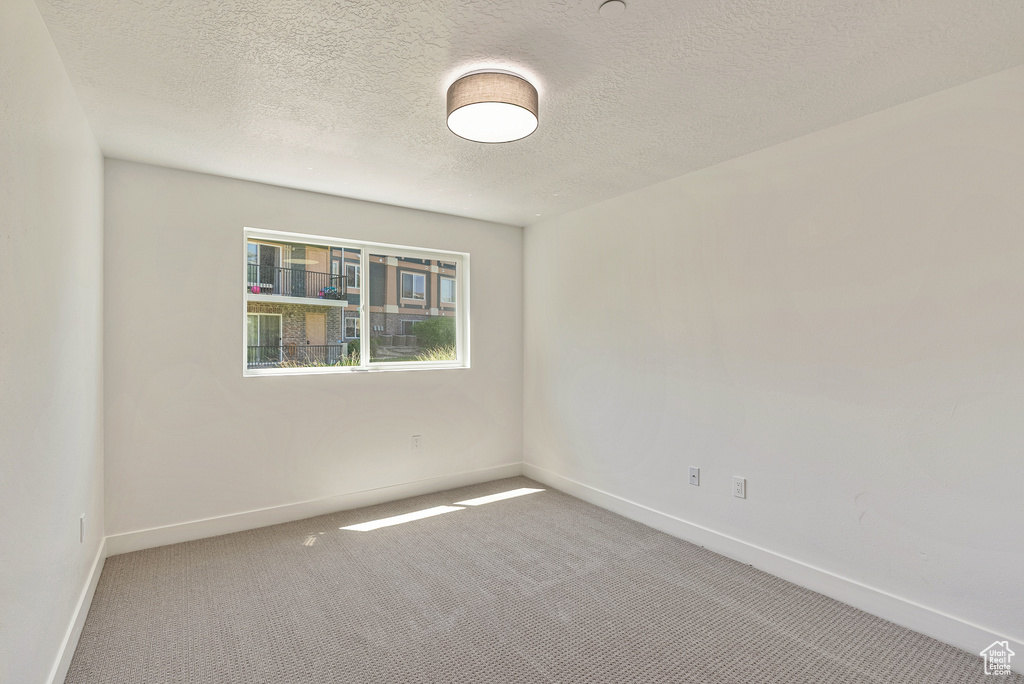 Spare room with carpet floors, baseboards, and a textured ceiling