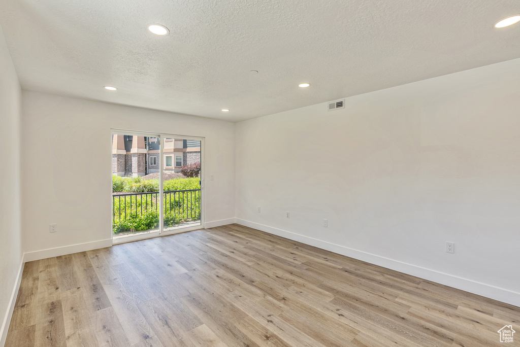 Spare room with baseboards, light wood finished floors, recessed lighting, and a textured ceiling
