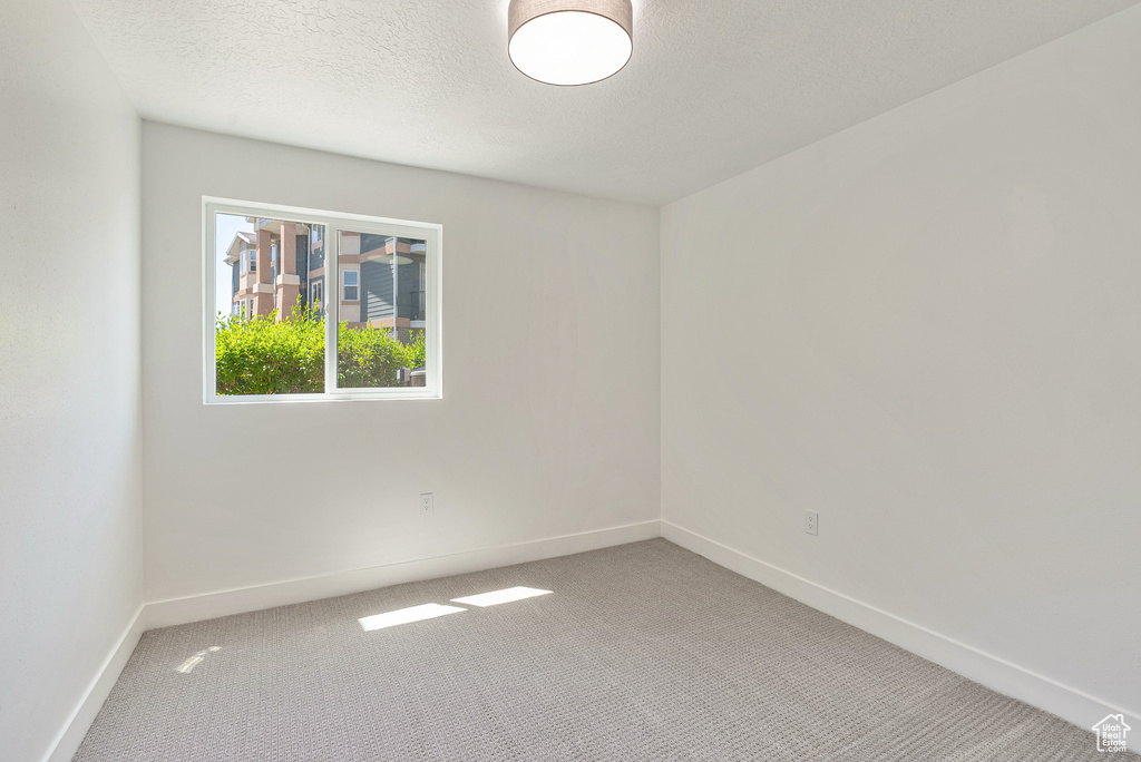 Carpeted empty room featuring baseboards and a textured ceiling