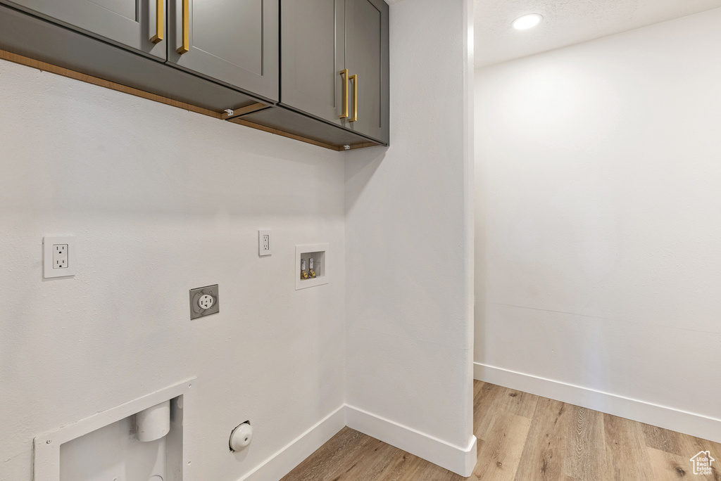 Laundry area with cabinet space, baseboards, light wood-type flooring, washer hookup, and electric dryer hookup
