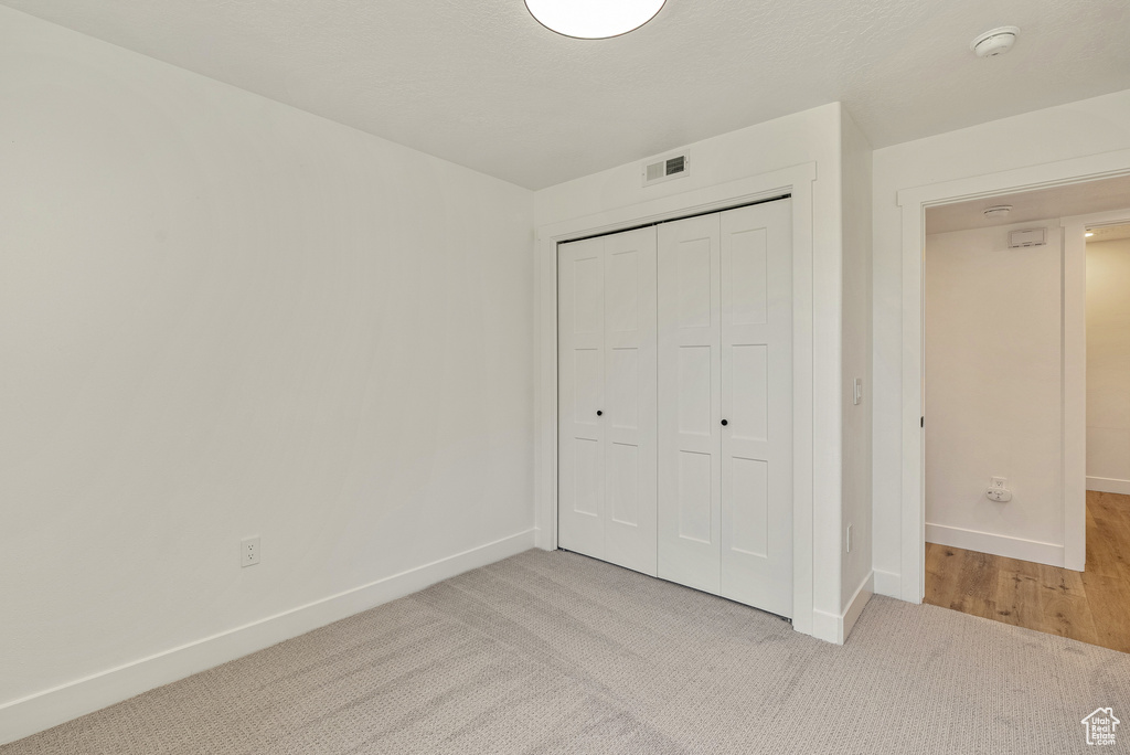 Unfurnished bedroom with light colored carpet, baseboards, and a closet