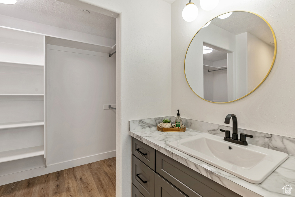 Bathroom with vanity, wood finished floors, a walk in closet, and baseboards