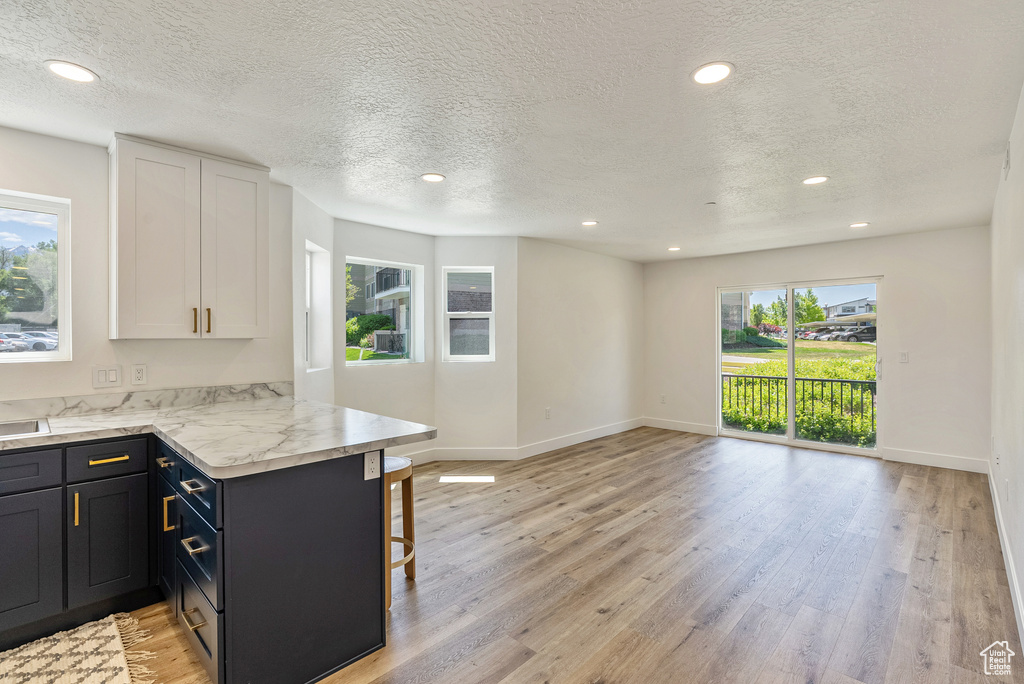 Kitchen with a kitchen breakfast bar, a peninsula, light wood-style floors, recessed lighting, and baseboards