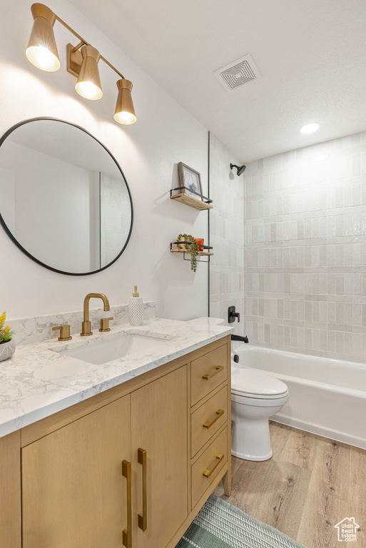 Bathroom with vanity, toilet, wood finished floors, and shower / washtub combination