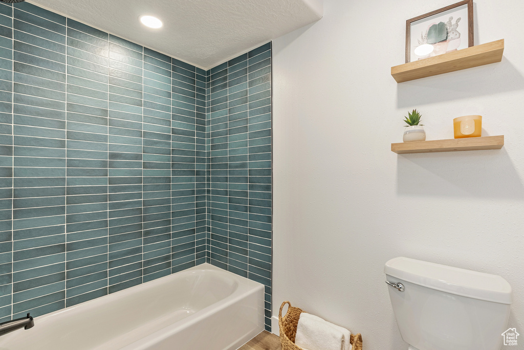 Full bath with toilet, shower / bathtub combination, and a textured ceiling