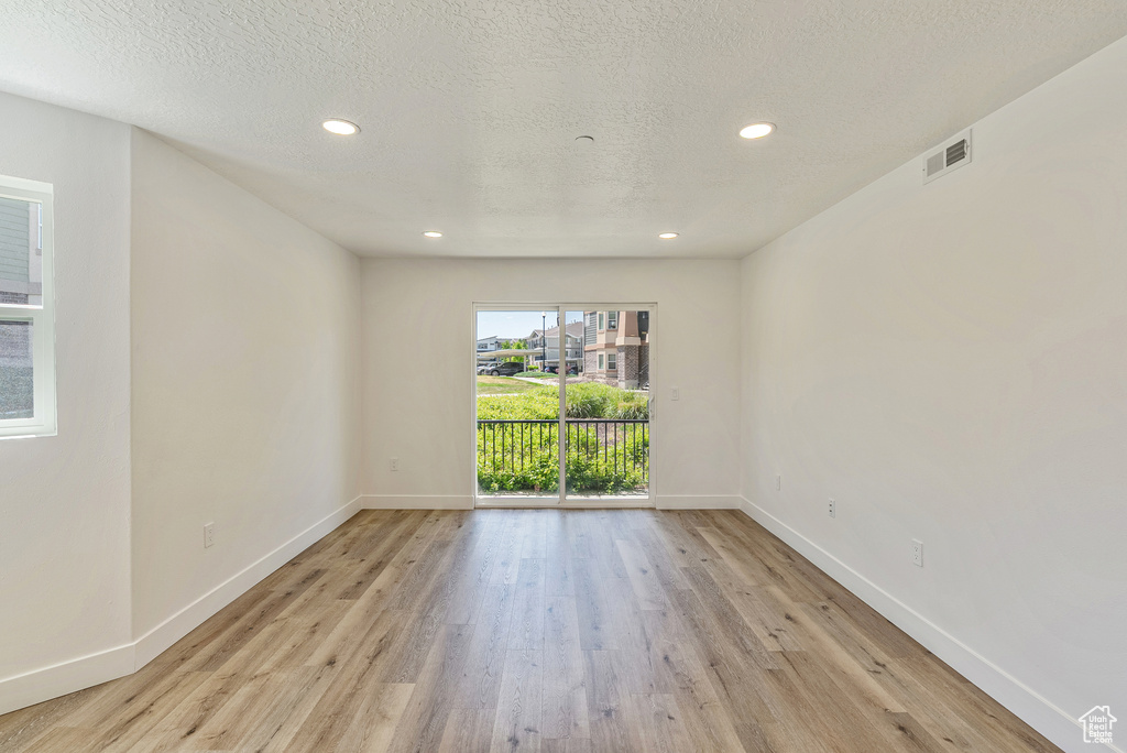 Unfurnished room with light wood-style flooring, baseboards, recessed lighting, and a textured ceiling