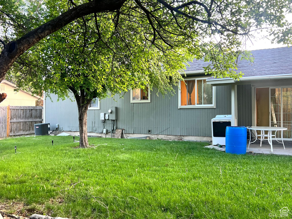 Back of house with central AC unit and roof with shingles
