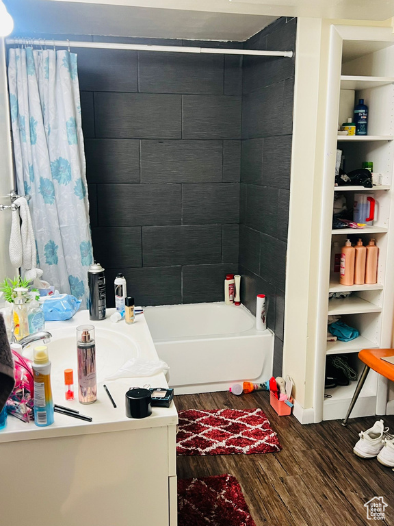 Bathroom with wood finished floors, shower / bath combination with curtain, and vanity