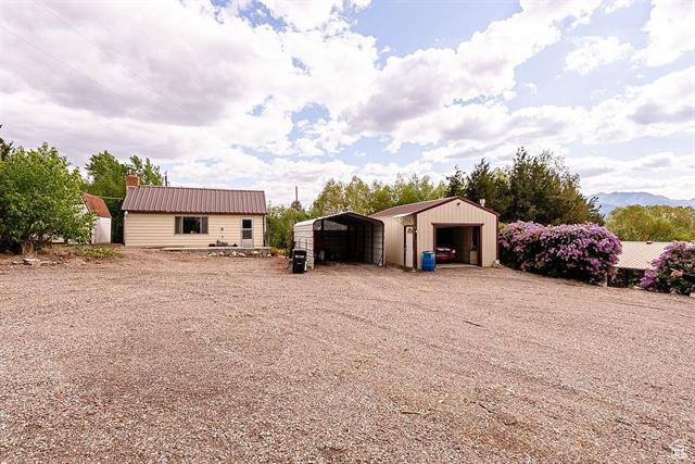 View of yard with a garage, an outbuilding, and driveway