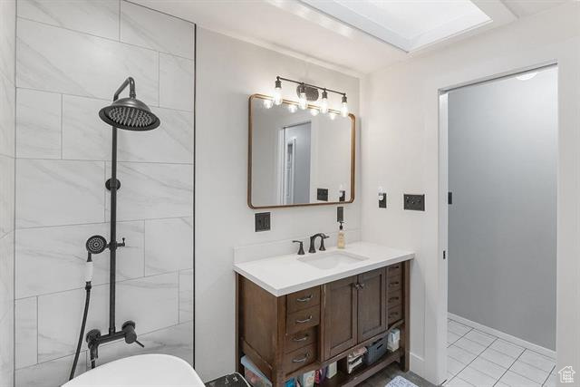 Bathroom featuring vanity, toilet, a tile shower, and tile patterned floors