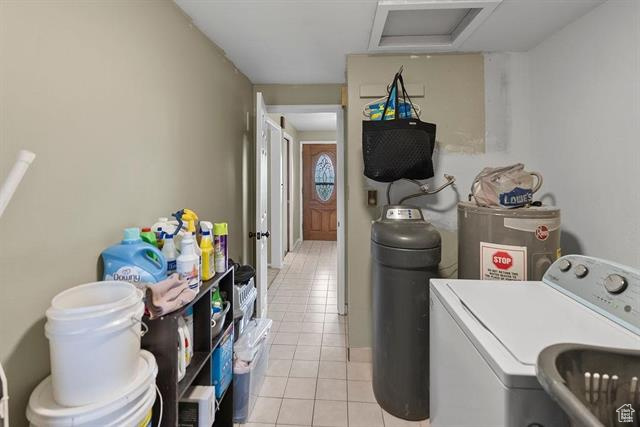 Laundry room featuring washer / dryer, water heater, attic access, and light tile patterned floors