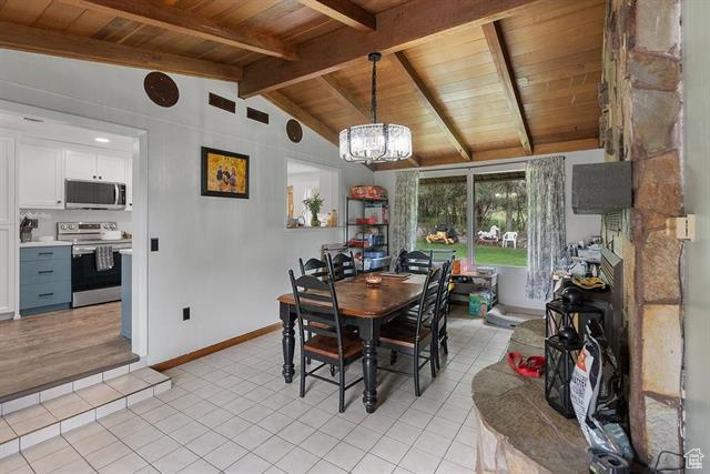 Dining area featuring wooden ceiling, light tile patterned floors, a chandelier, and baseboards