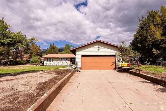 Ranch-style home with concrete driveway, a garage, and a front yard