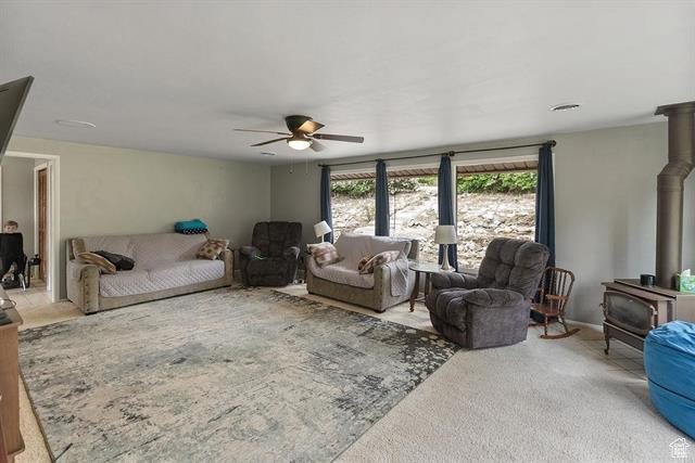 Carpeted living area featuring a wood stove and ceiling fan