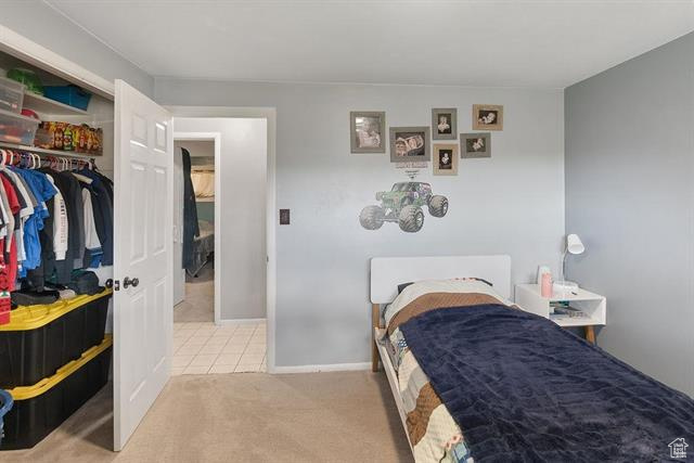 Tiled bedroom featuring carpet, a closet, and baseboards
