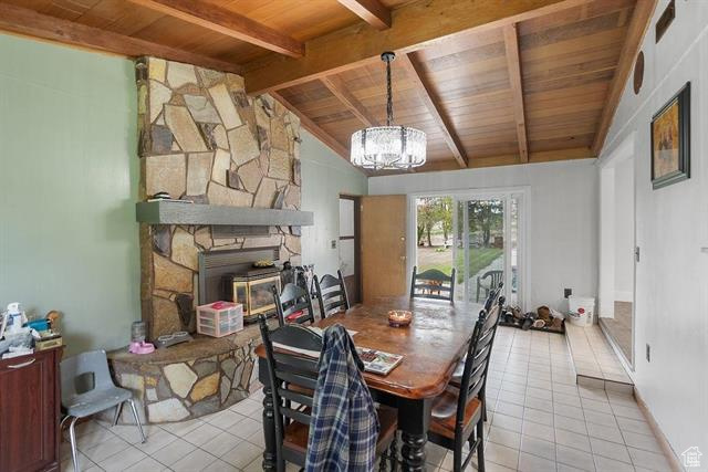Dining area featuring wood ceiling, light tile patterned floors, a chandelier, and a fireplace