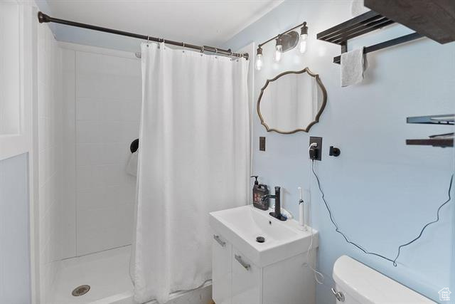 Full bath featuring toilet, a shower with curtain, and vanity