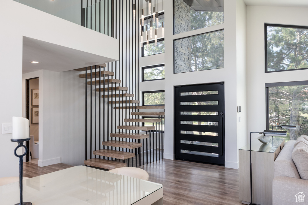 Entryway with a high ceiling, wood finished floors, stairs, and healthy amount of natural light