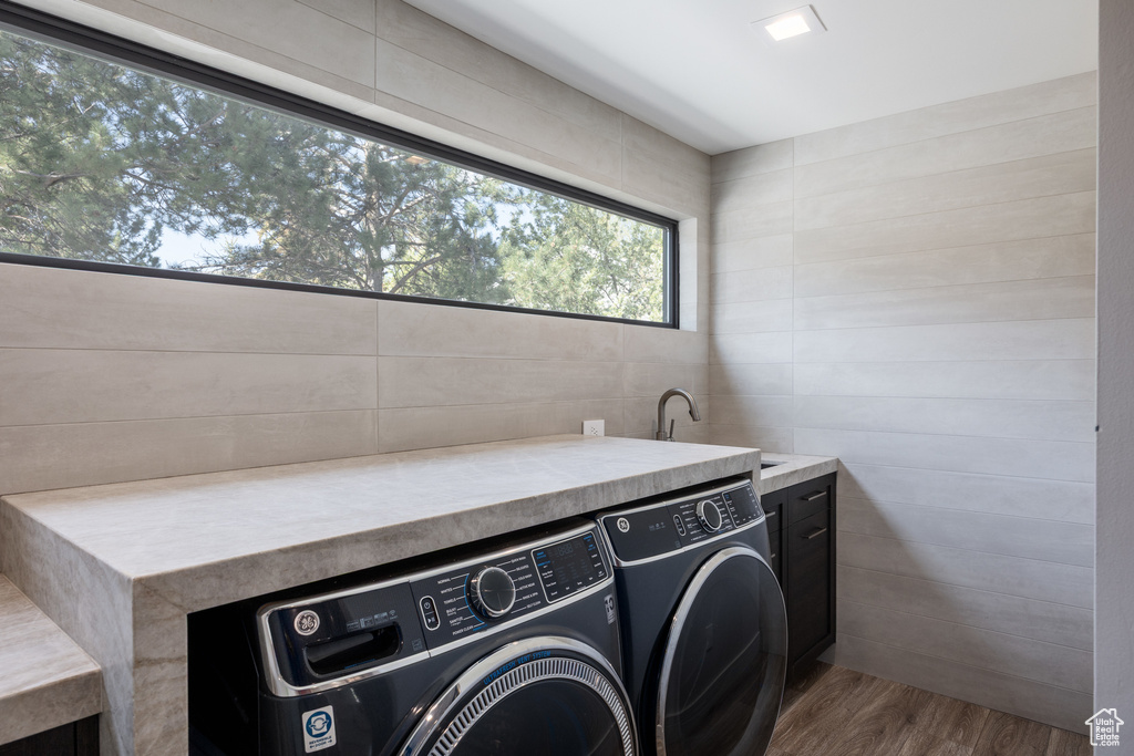 Laundry room featuring separate washer and dryer, cabinet space, and wood finished floors