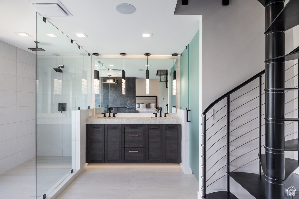 Full bath with a shower stall, double vanity, and tile patterned flooring