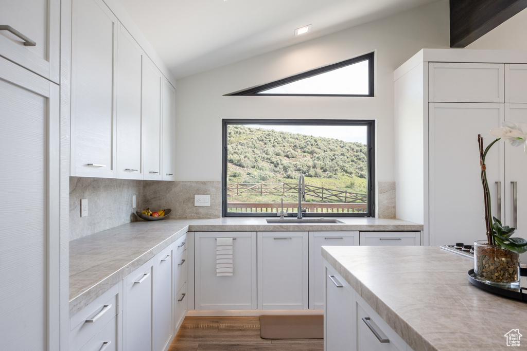 Kitchen with white cabinets, a sink, light countertops, and backsplash