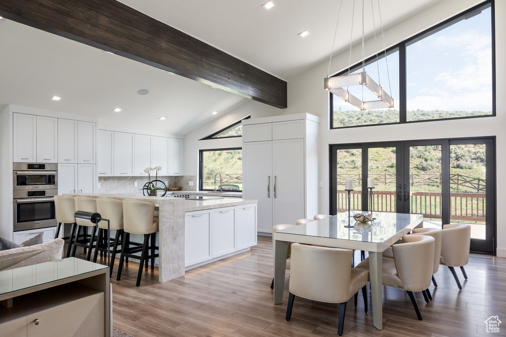 Dining room featuring high vaulted ceiling, beam ceiling, light wood-type flooring, french doors, and recessed lighting