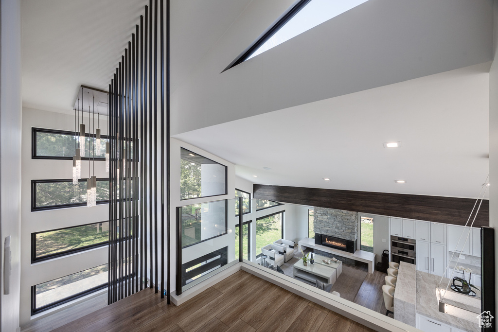 Stairs with wood finished floors, plenty of natural light, a fireplace, and recessed lighting