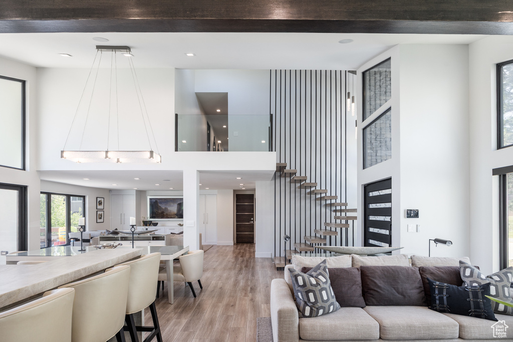 Living area featuring a towering ceiling, light wood finished floors, and stairs