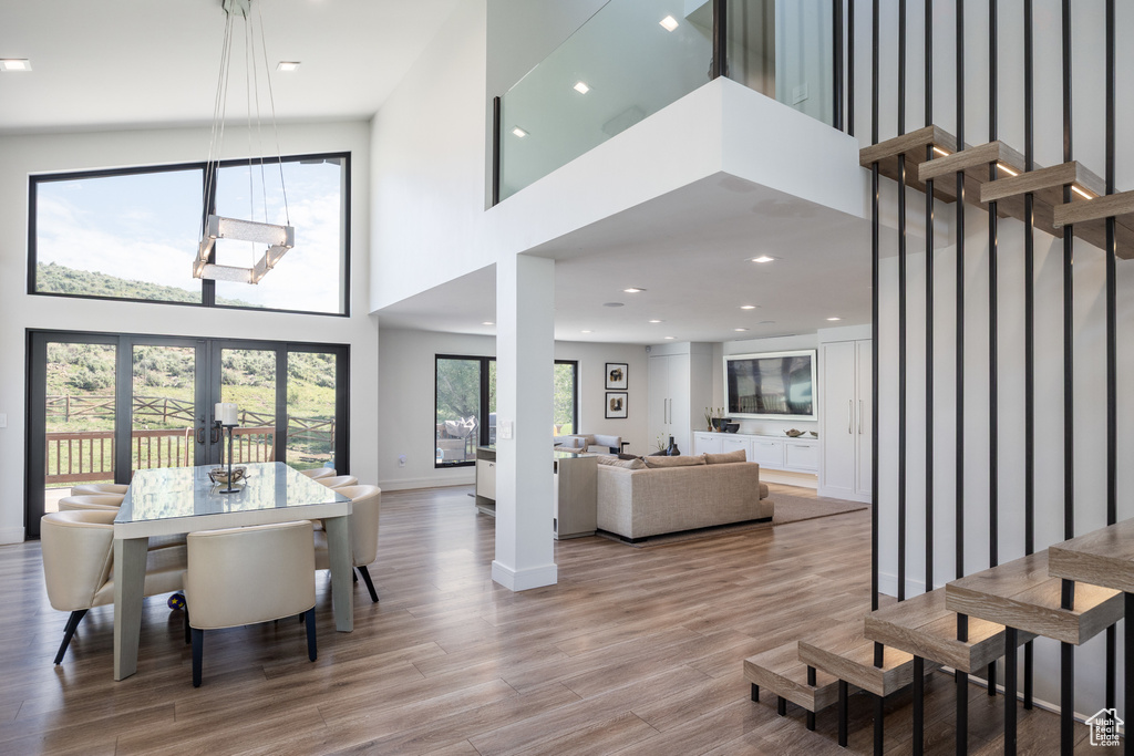 Dining room with a high ceiling, wood finished floors, recessed lighting, and french doors