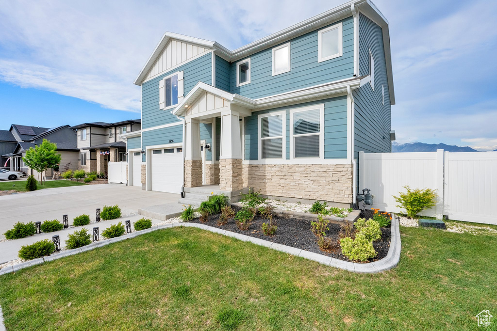 Craftsman-style home featuring an attached garage, board and batten siding, stone siding, and concrete driveway