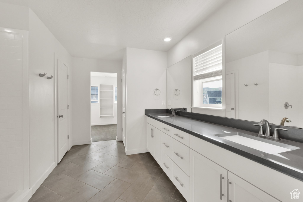 Bathroom with double vanity, tile patterned flooring, baseboards, a closet, and recessed lighting