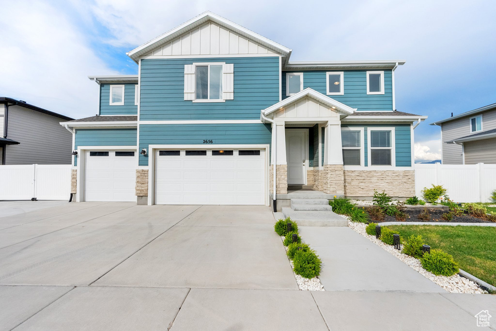 View of front of home featuring a garage, board and batten siding, stone siding, and driveway