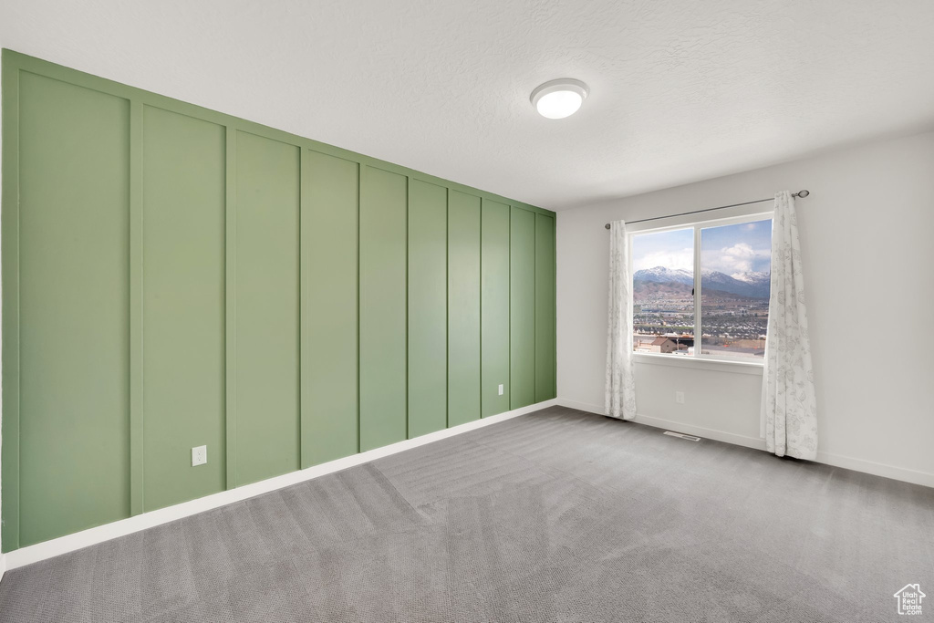 Empty room with carpet, baseboards, and a textured ceiling
