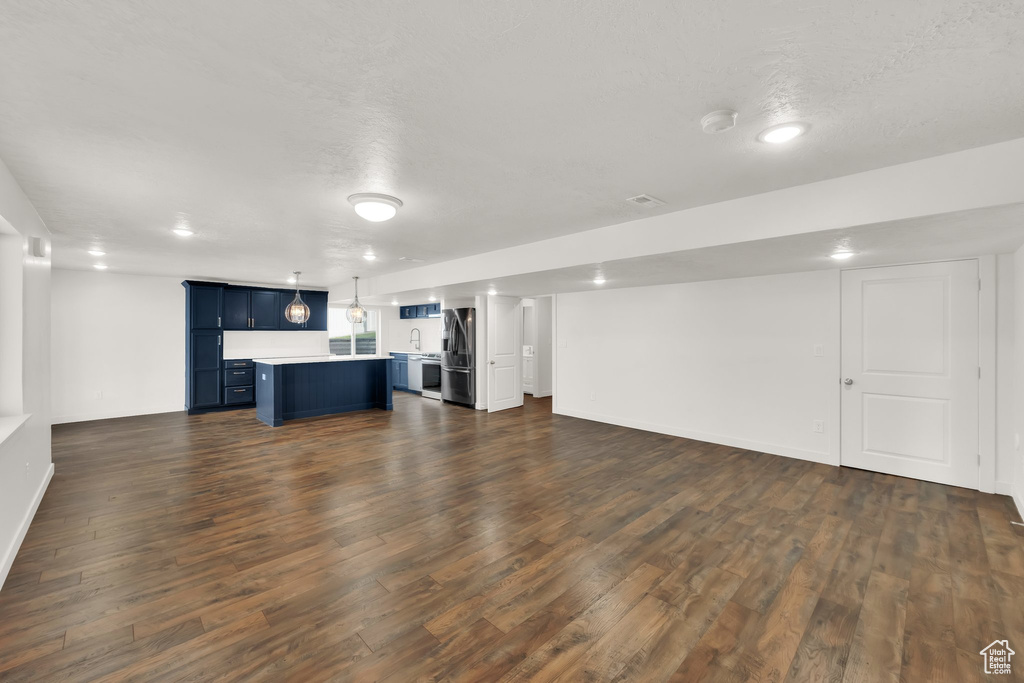Unfurnished living room featuring dark wood-style flooring, baseboards, and recessed lighting