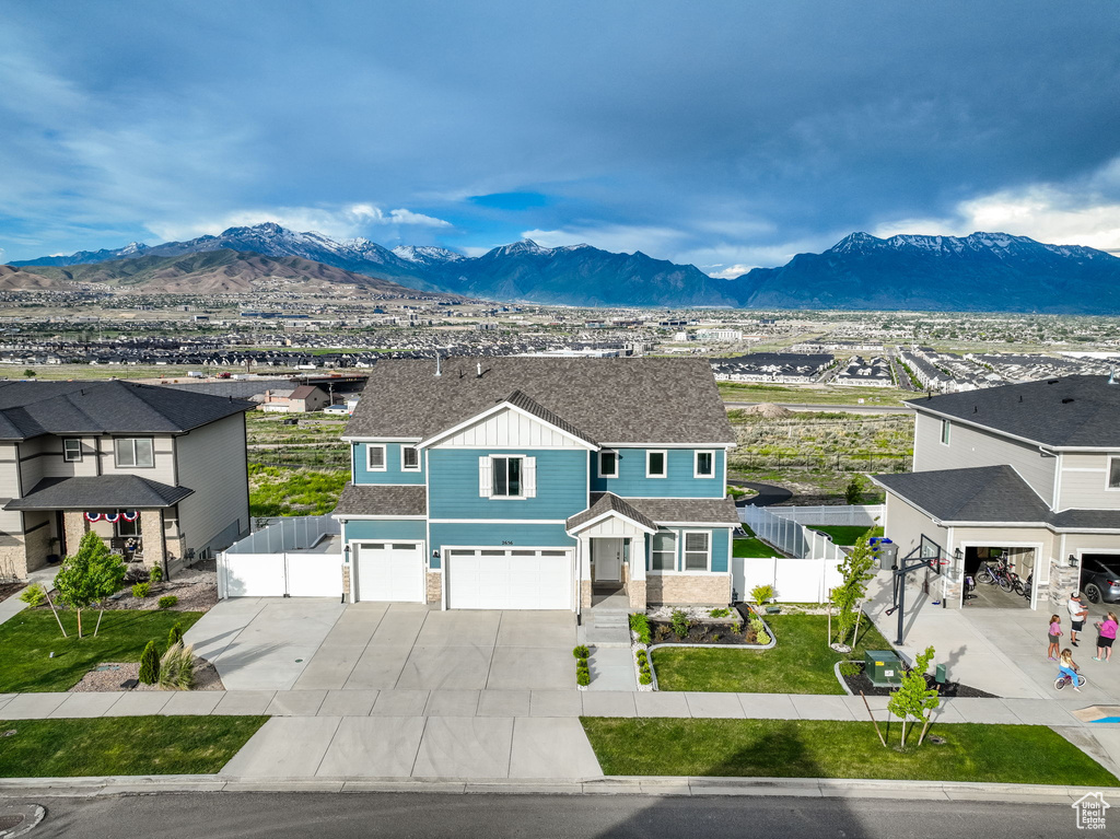 View of front of property with board and batten siding, a mountain view, a garage, concrete driveway, and stone siding