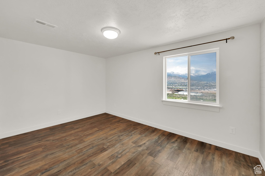 Spare room with dark wood-type flooring and baseboards