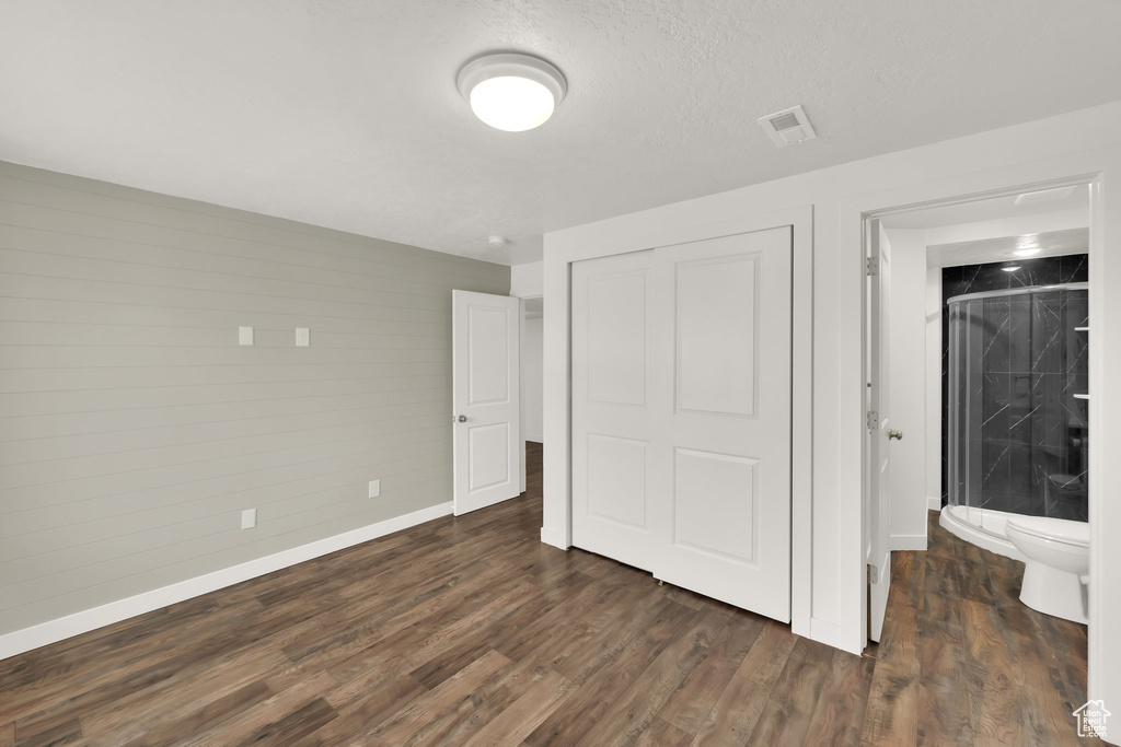Unfurnished bedroom featuring baseboards, a closet, and dark wood-style floors
