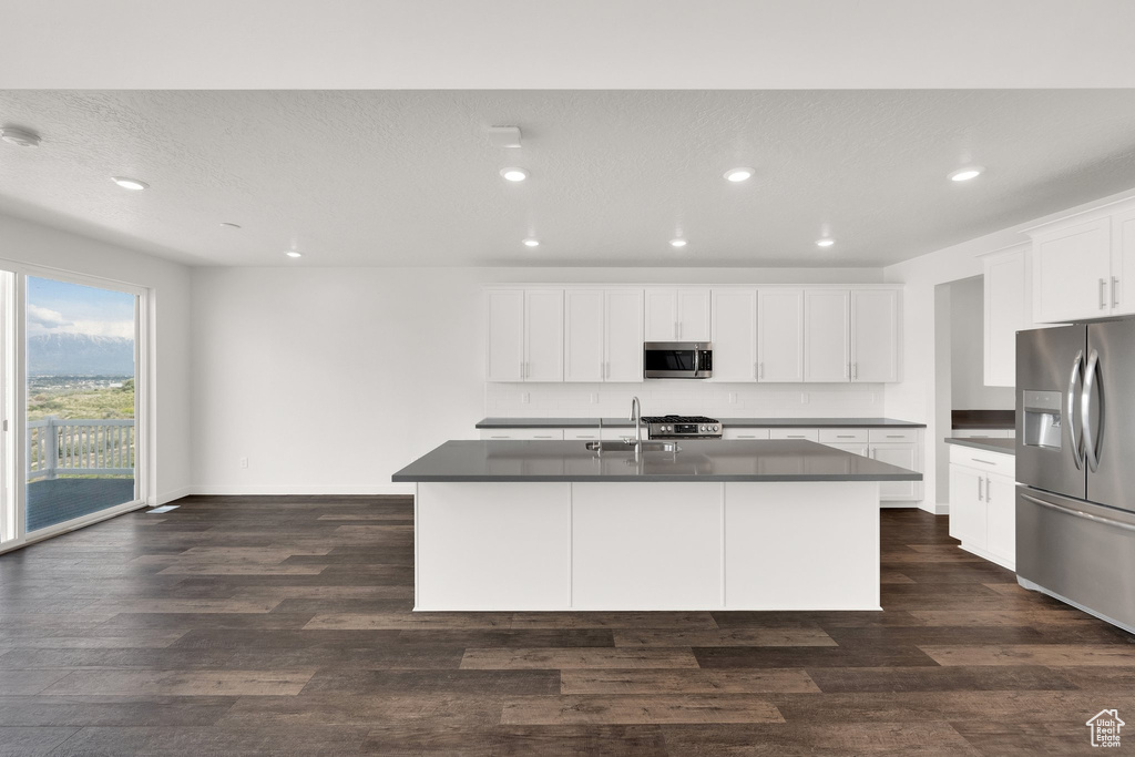 Kitchen with appliances with stainless steel finishes, dark countertops, recessed lighting, and dark wood-style flooring