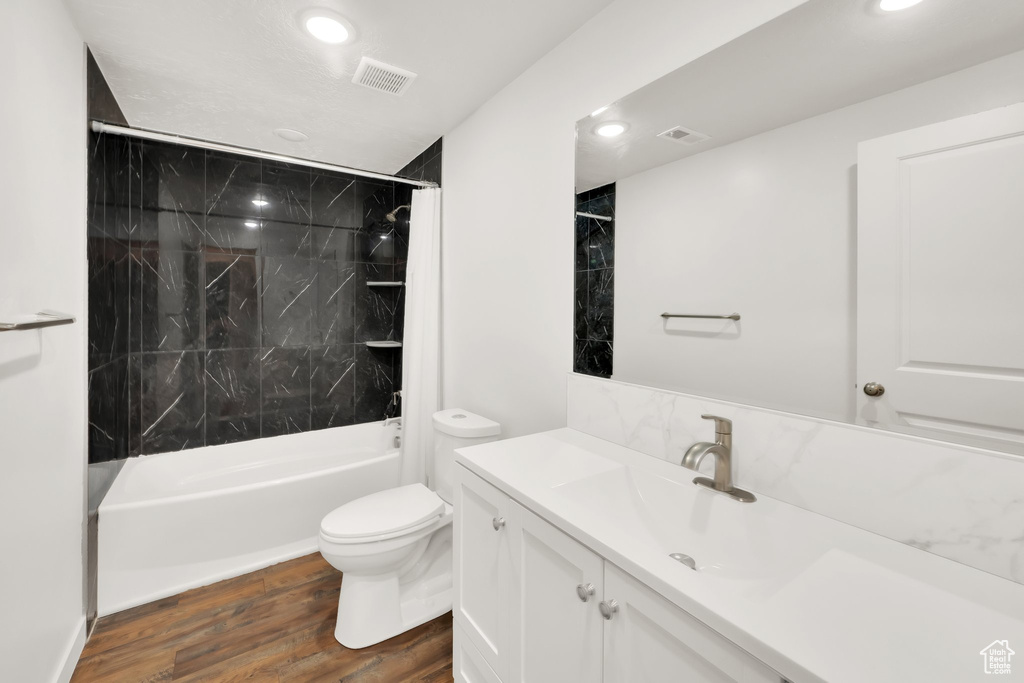 Bathroom with recessed lighting, toilet, vanity, wood finished floors, and  shower combination