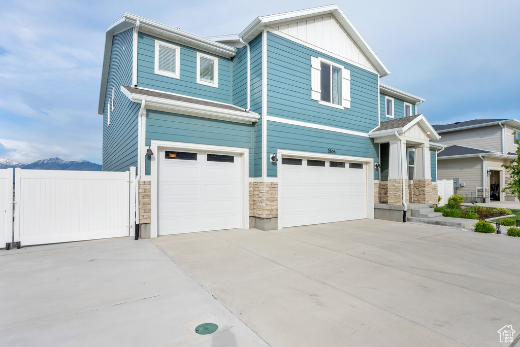 View of front facade with stone siding, a garage, concrete driveway, and board and batten siding