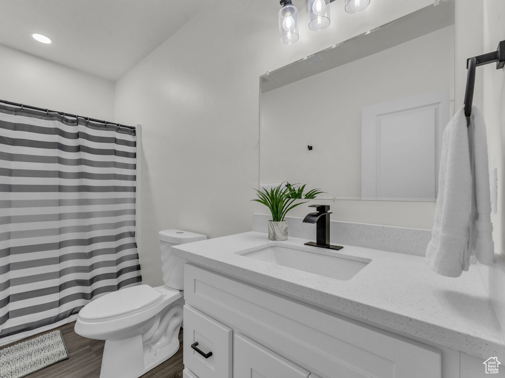Full bathroom with toilet, vanity, wood finished floors, a shower with curtain, and recessed lighting