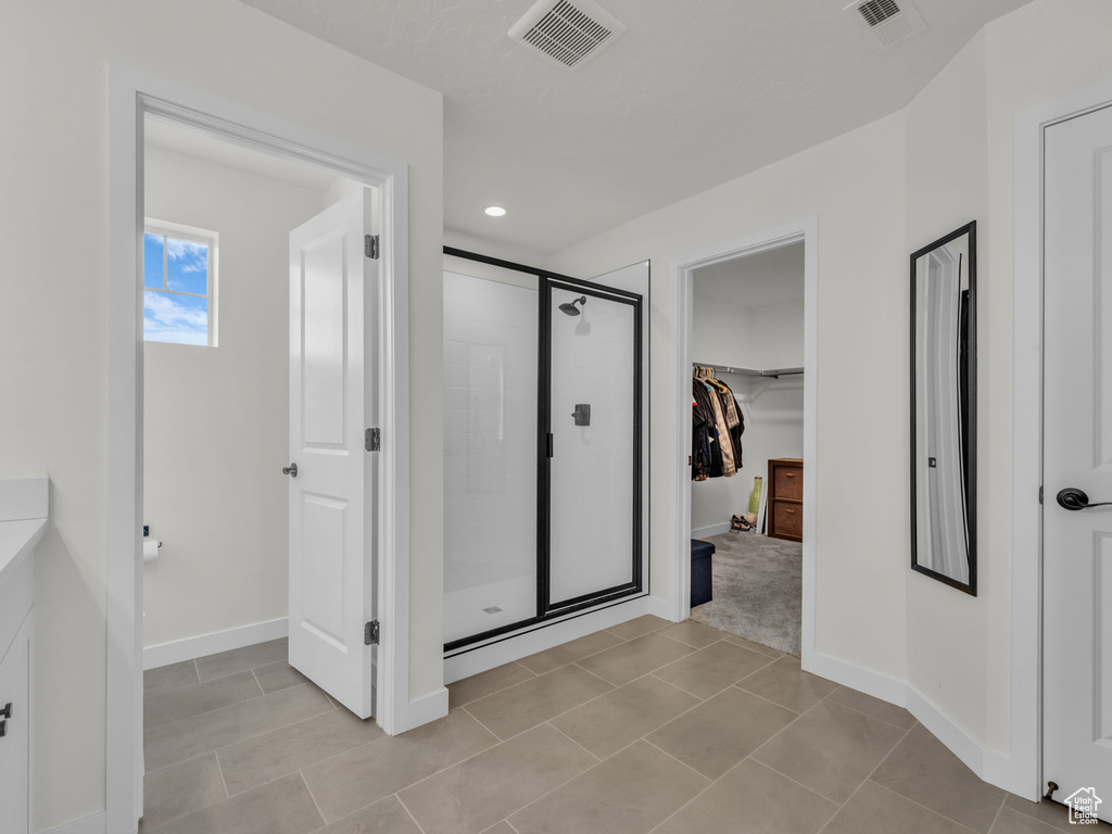 Full bathroom with a stall shower, a walk in closet, baseboards, recessed lighting, and tile patterned floors