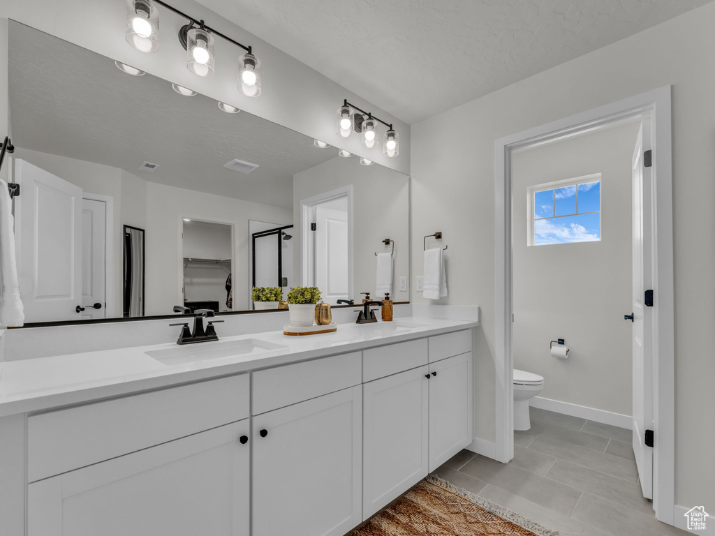 Full bath with double vanity, toilet, baseboards, an enclosed shower, and tile patterned floors