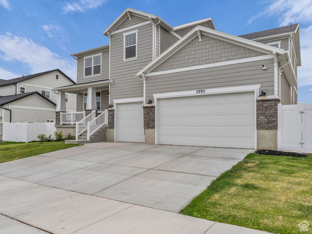 Craftsman-style house featuring concrete driveway, stone siding, an attached garage, and a porch
