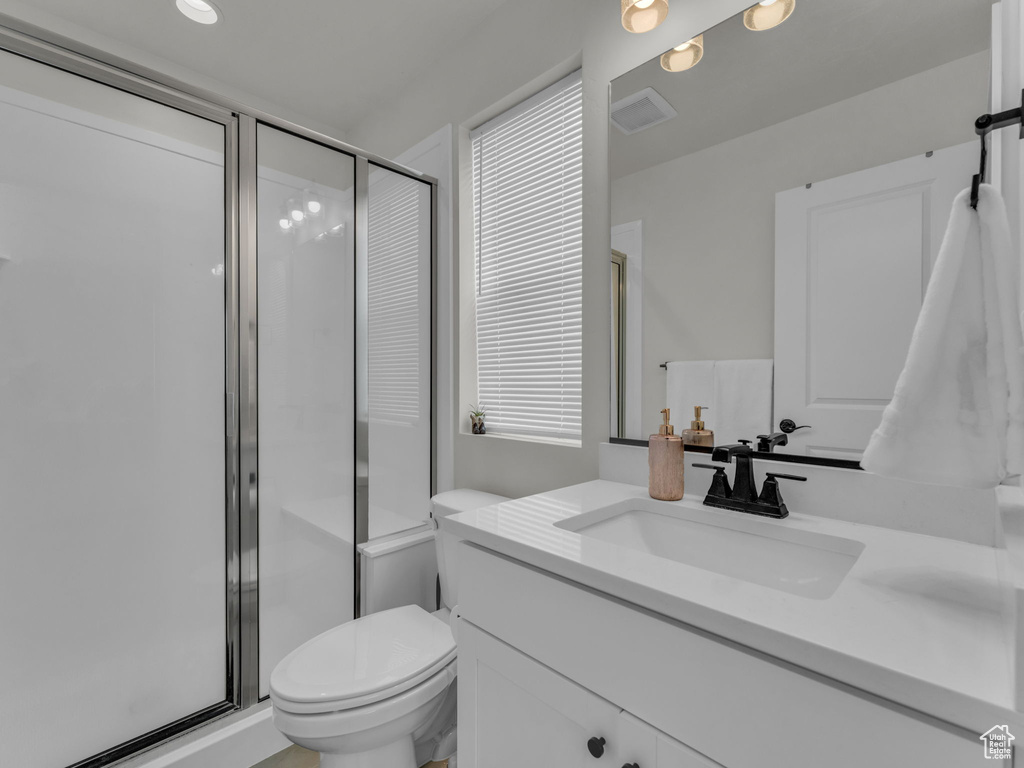 Bathroom featuring vanity, toilet, and a shower stall