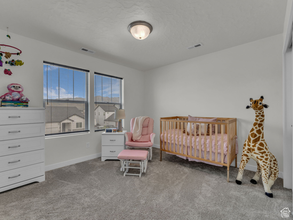 Carpeted bedroom with baseboards and a crib
