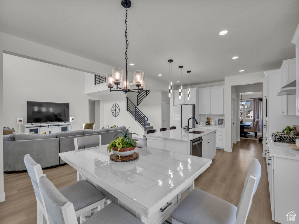 Dining room featuring recessed lighting, light wood-style floors, a chandelier, and stairs