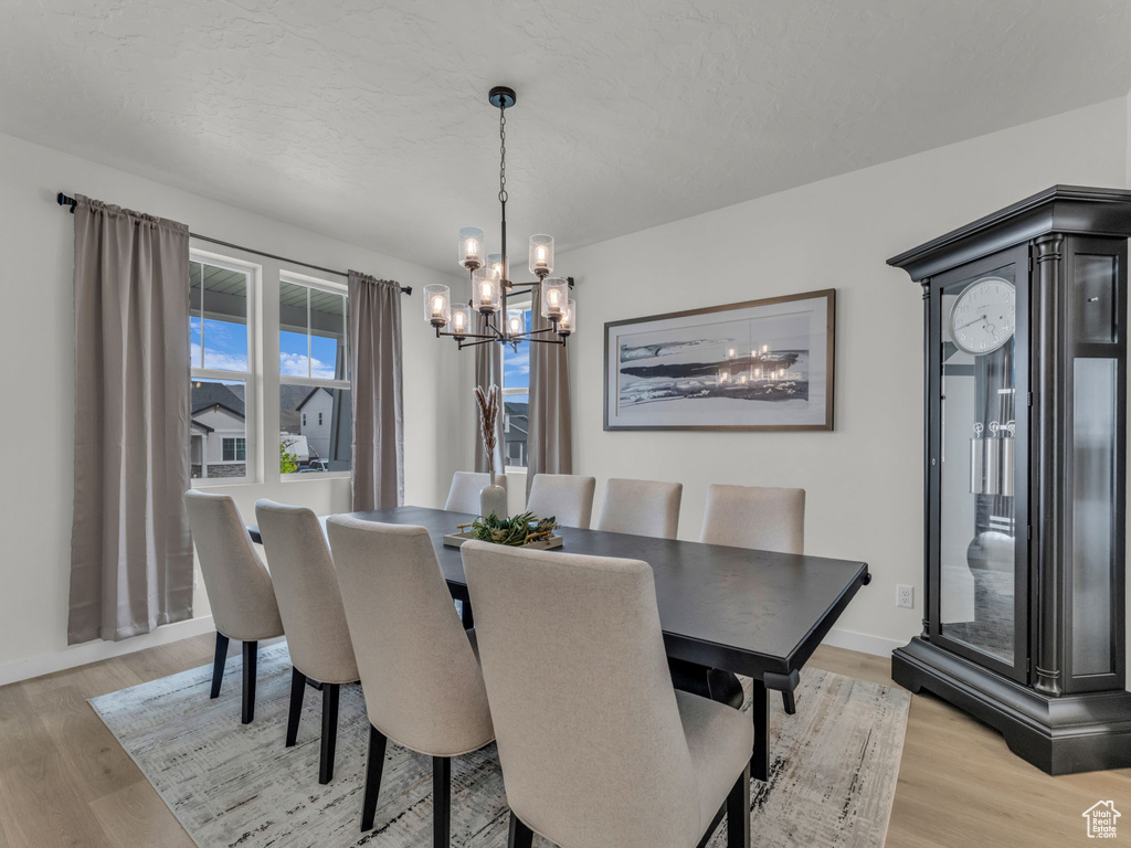 Dining room with a chandelier, light wood-style floors, and baseboards